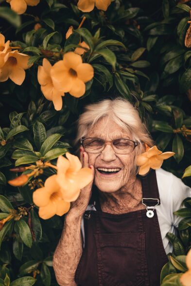 Old woman laughing in flowers