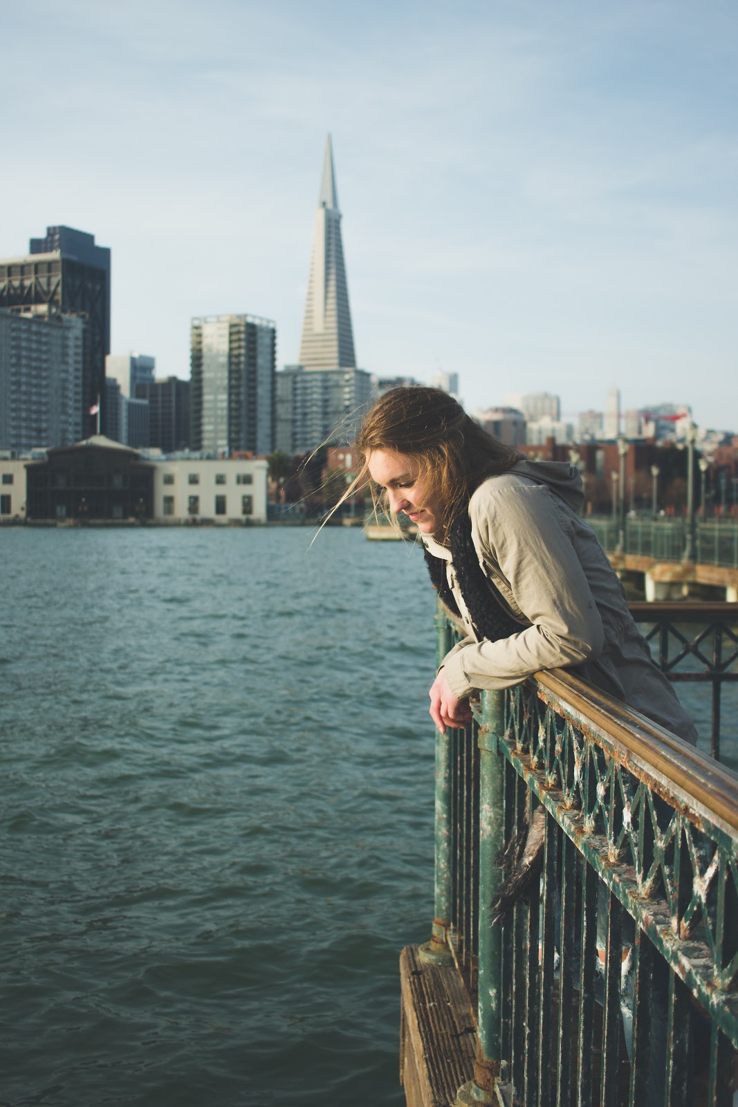 A woman looks calm posing at the end of a pier in a city whilst she prepares for life after quarantine